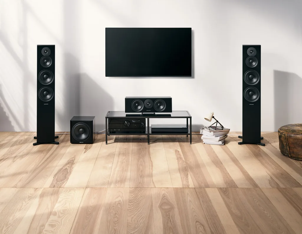 Home theater Dynaudio Emit em sala clara: duas caixas de chão Emit 50, caixa central Emit 25C, subwoofer e TV na parede