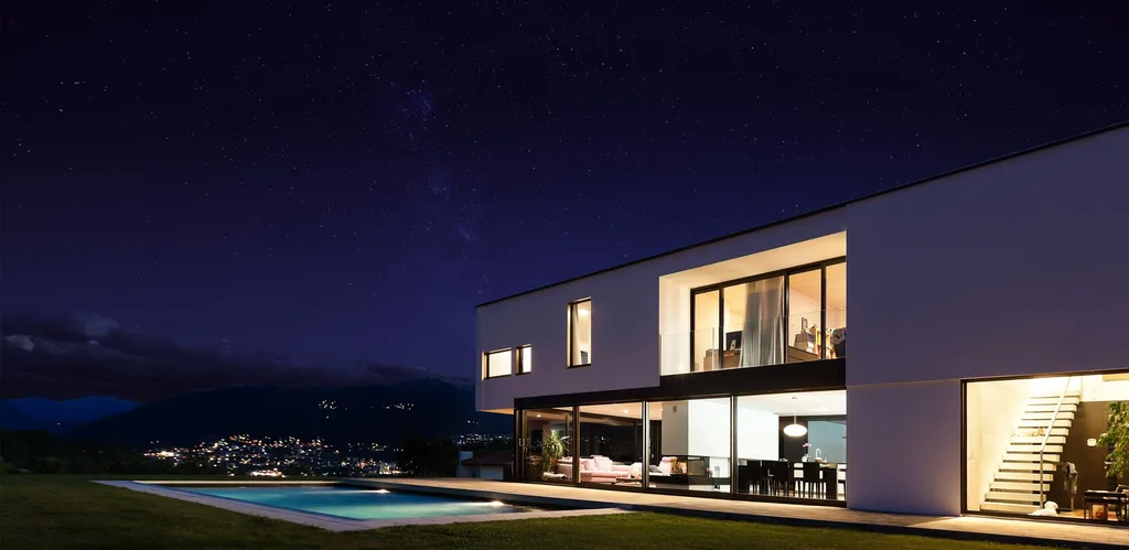Casa moderna iluminada à noite, com piscina e vista para as montanhas