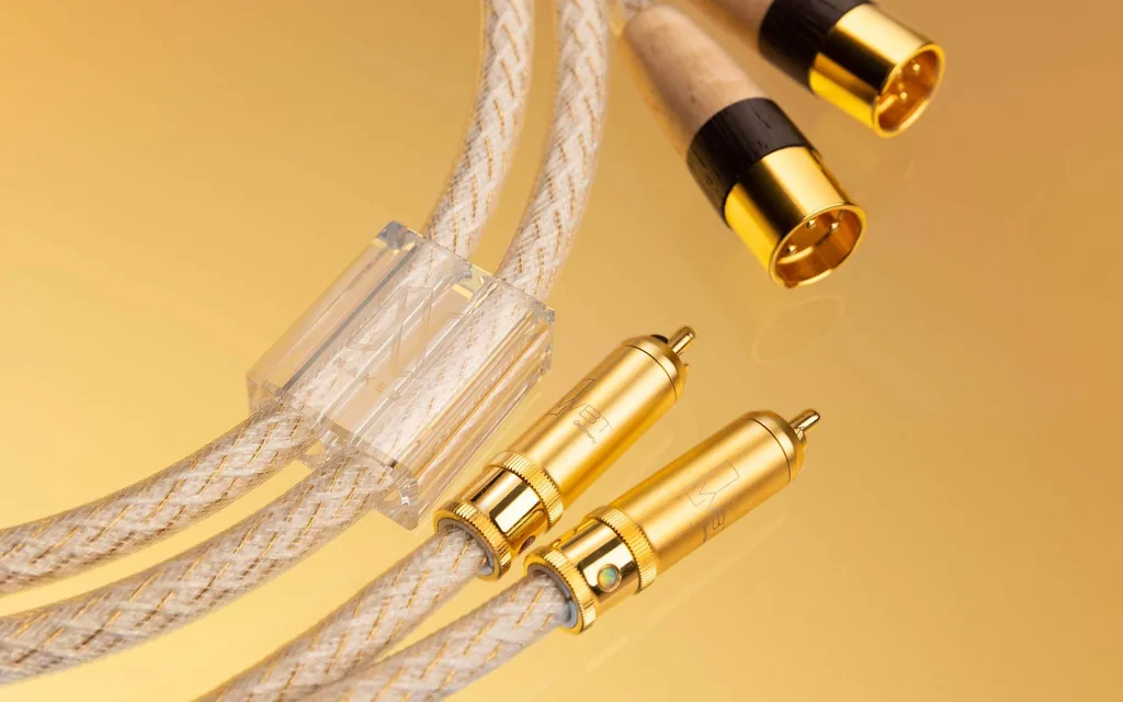 Cabos de interconexão Kimber Kable Naked, com conectores RCA e XLR dourados, sobre fundo âmbar