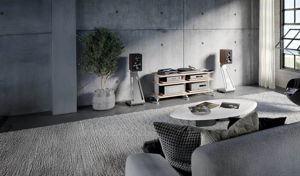 Ilustração do fabricante: sala com parede de concreto, rack de áudio Solid Tech e caixas acústicas em suportes.