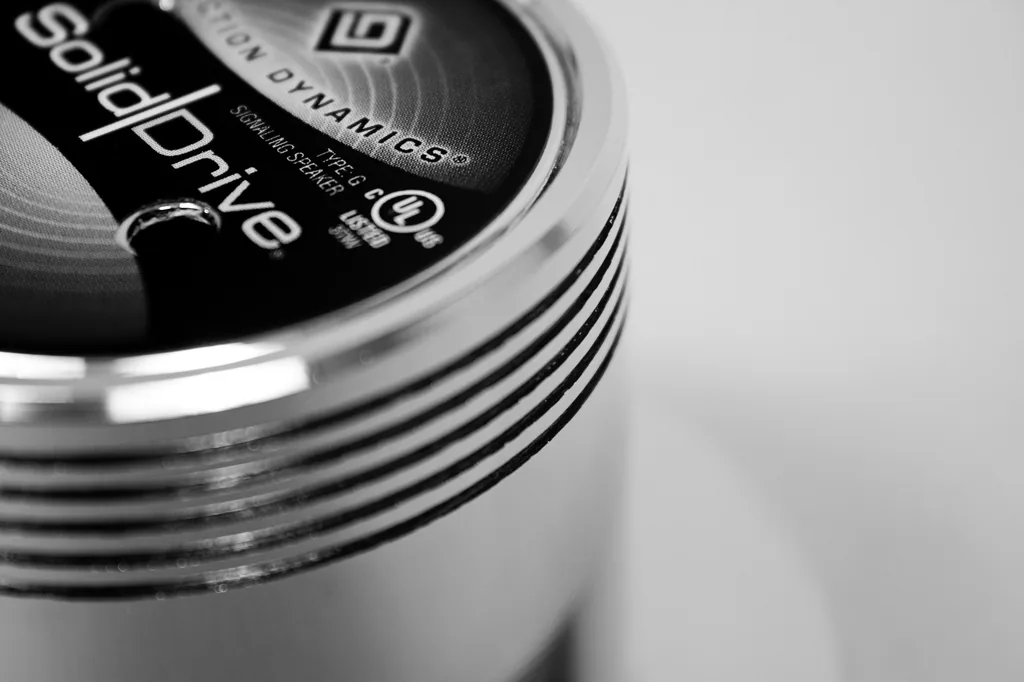 Detalhe em preto e branco do transdutor SolidDrive SD-1, que transforma paredes, vidros e outras superfícies em caixas acústicas invisíveis