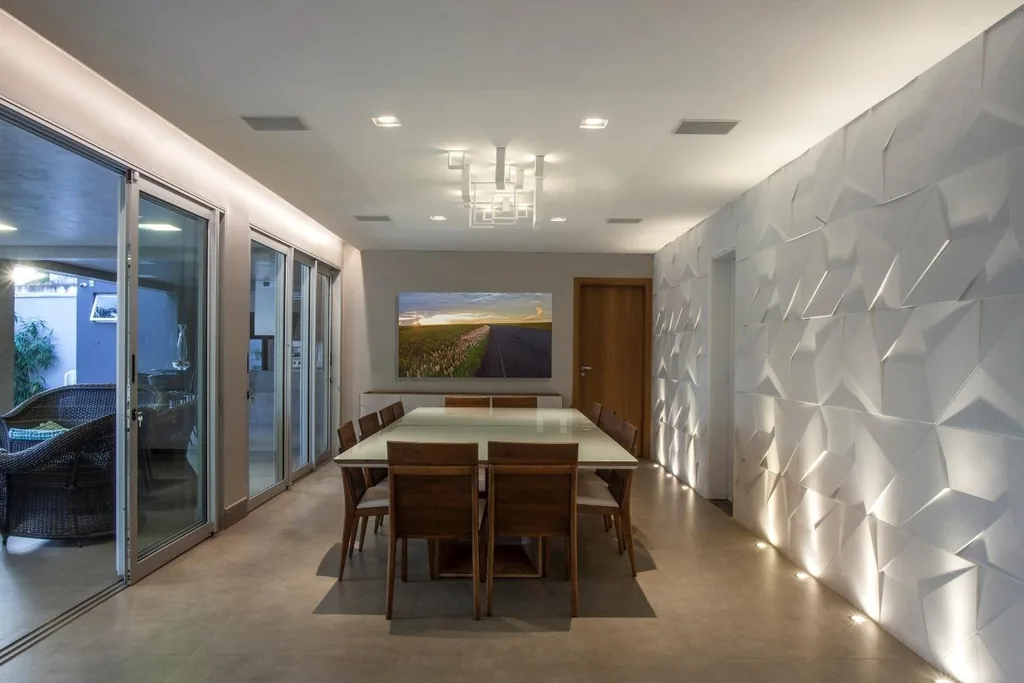 Sala de jantar com mesa longa, parede de revestimento em relevo e iluminação embutida