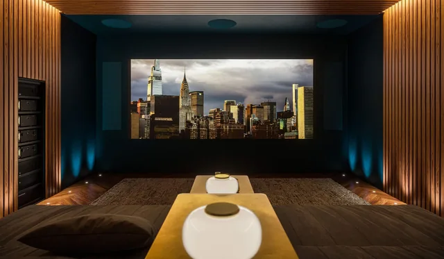 Sala de cinema com tela de projeção, painéis de madeira e eletrônicos Marantz embutidos na parede